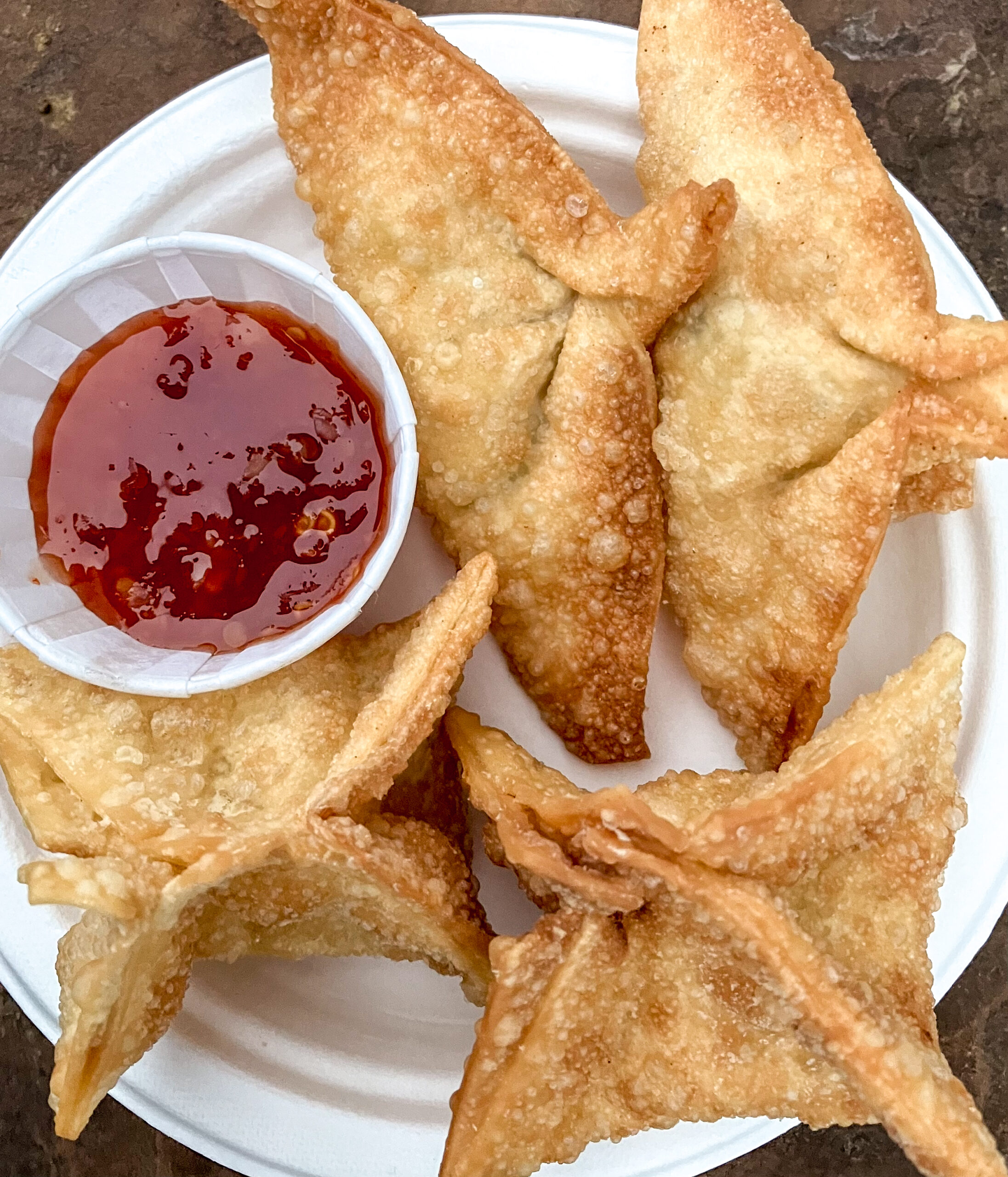 Blueberry rangoon, crispy fried wonton parcels dusted with powdered sugar on a white plate