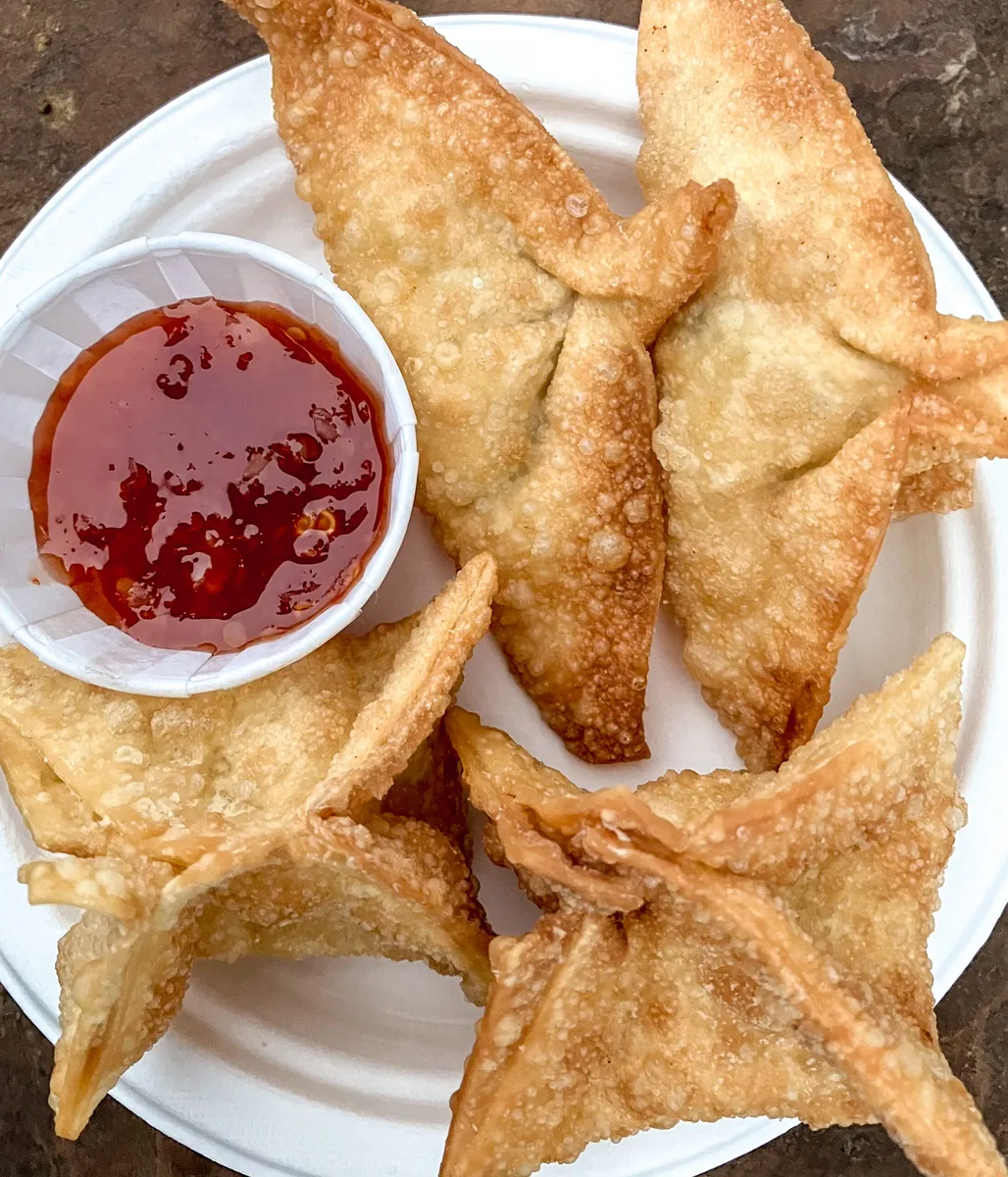 Blueberry rangoon, crispy fried wonton parcels dusted with powdered sugar on a white plate